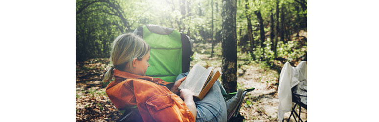 girl camping and reading a book