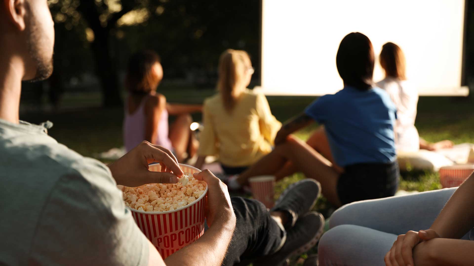 A guy eating popcorn at an outdoor cinema