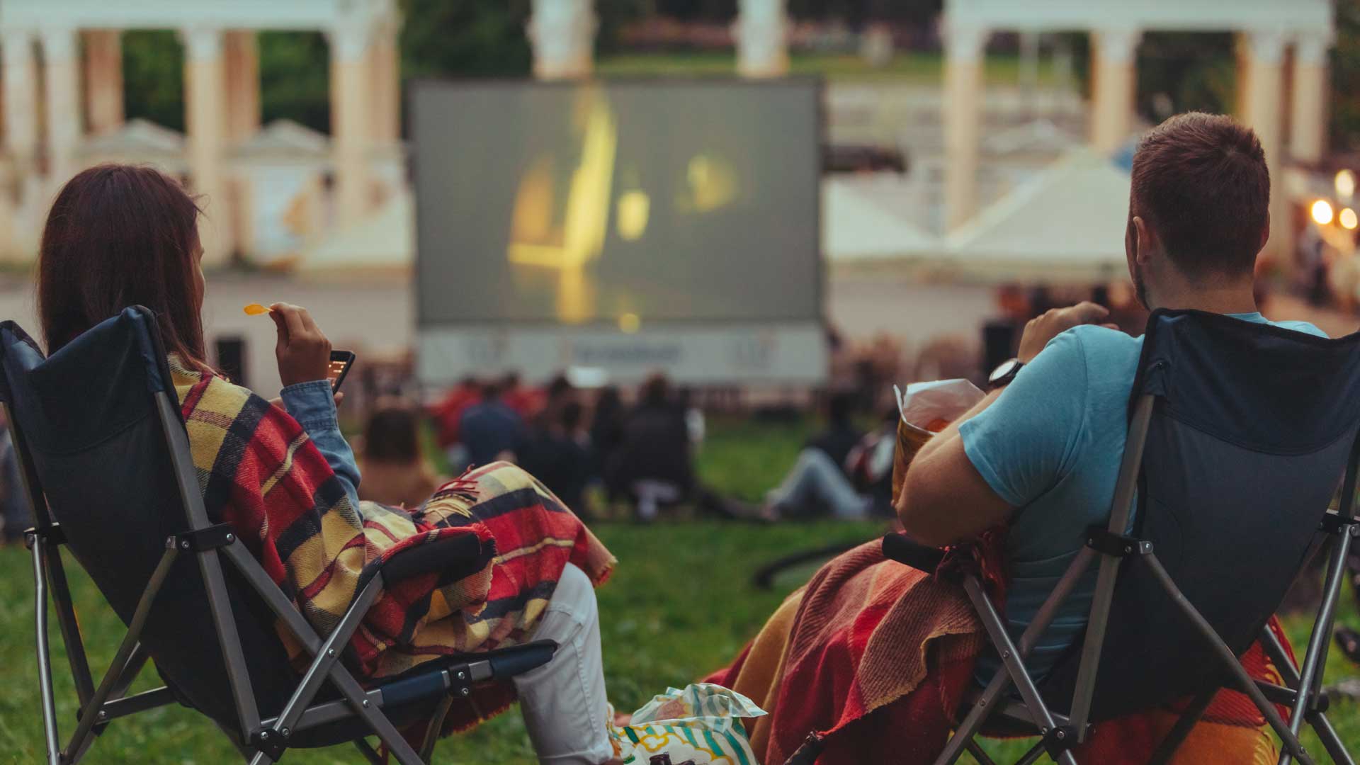 Couple sitting on folding chair at outdoor cinema