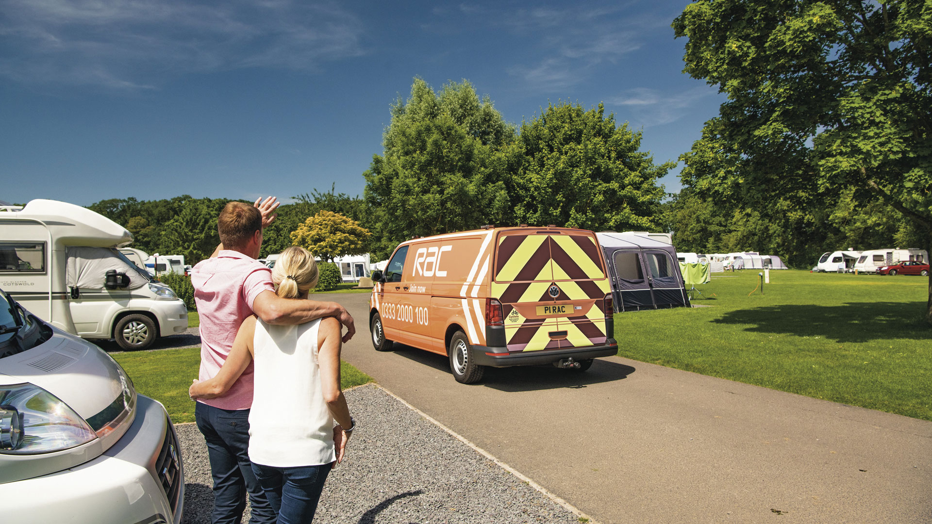 RAC recovery van on a campsite with a couple in the foreground.  