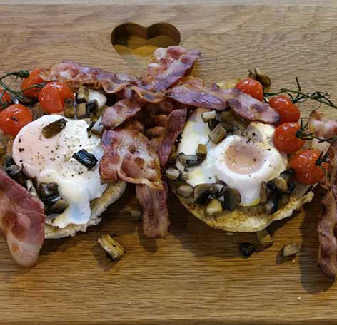 Muffin, poached eggs, cherry tomatoes and streaky bacon